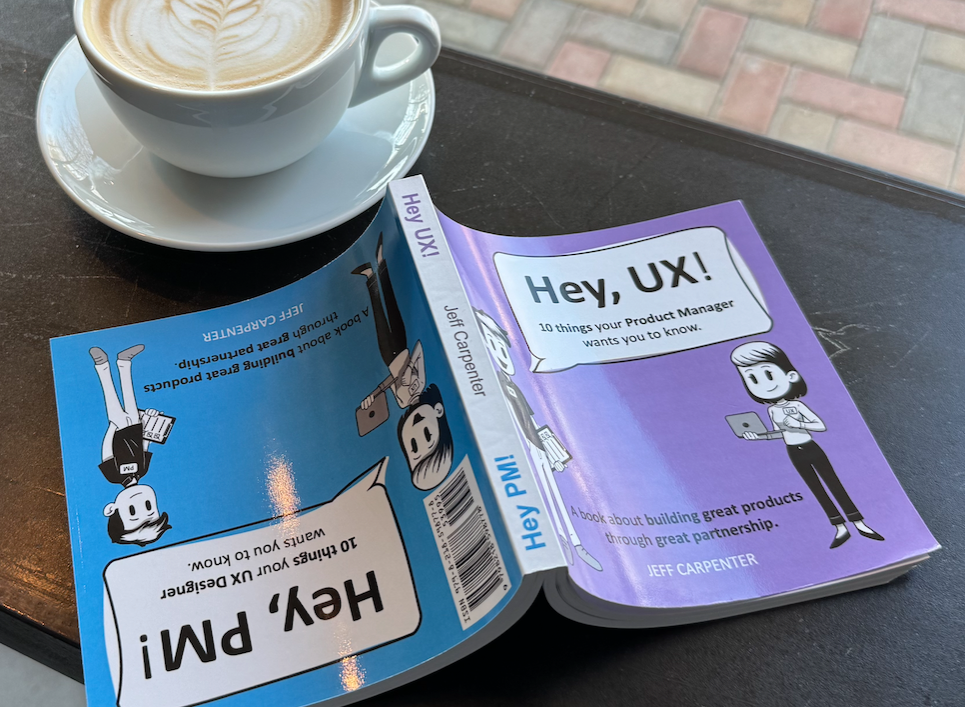 Hey, UX! and Hey, PM! books on a table with coffee